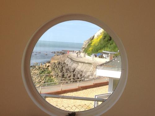anorthole window with a view of a beach and the ocean at PORTHOLES in Ventnor