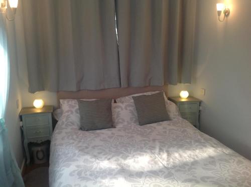 a bedroom with a white bed with two night stands at PORTHOLES in Ventnor