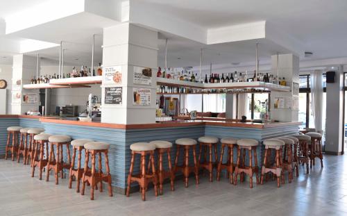 un bar con un montón de taburetes en una habitación en Apartamentos Arcos Playa en S'Illot