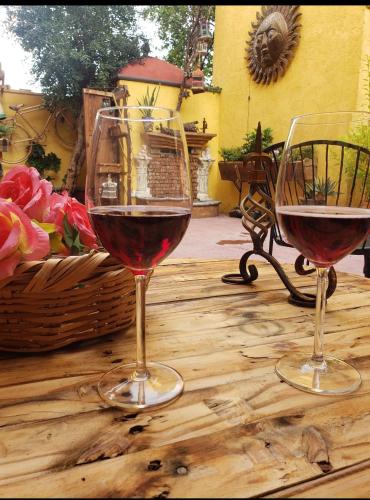 two glasses of red wine sitting on a wooden table at Hotel Posada de la Conspiración in Dolores Hidalgo