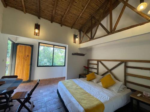 a bedroom with a bed with yellow pillows and a table at Hotel Casas de Campo El Ciruelo in San Gil