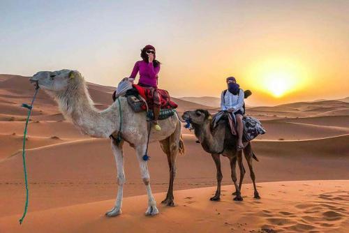 two people riding on the camel in the desert at Chigaga Luxury Camp in Mhamid