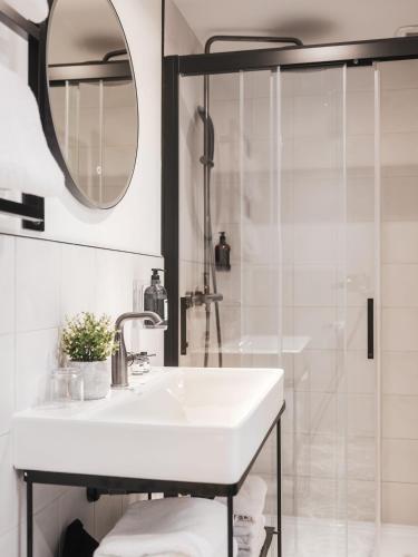 a white bathroom with a sink and a shower at Maisons du Monde Hotel & Suites - Nantes in Nantes