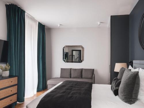 a bedroom with a bed and a couch and a mirror at Maisons du Monde Hotel & Suites - Nantes in Nantes