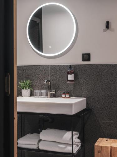 a bathroom with a white sink and a mirror at Maisons du Monde Hotel & Suites - Nantes in Nantes