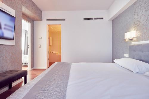 a bedroom with a white bed and a flat screen tv at MyContinental Sibiu in Sibiu