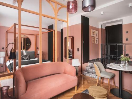 a living room with a pink couch and a bed at Maisons du Monde Hotel & Suites - Nantes in Nantes