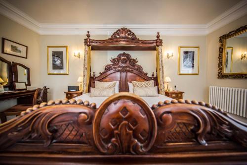 a large wooden bed with a wooden frame in a bedroom at Goldsborough Hall in Knaresborough