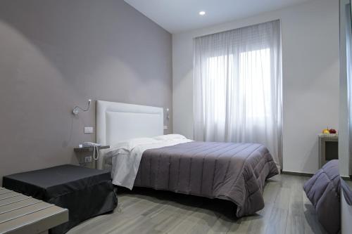 a white bedroom with a bed and a window at Hotel Bruman Salerno in Salerno