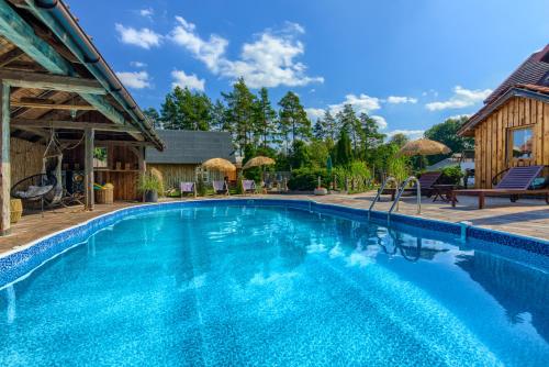 a swimming pool in a resort with a house at Oaza Mazurska - Domek z kominkiem in Piecki