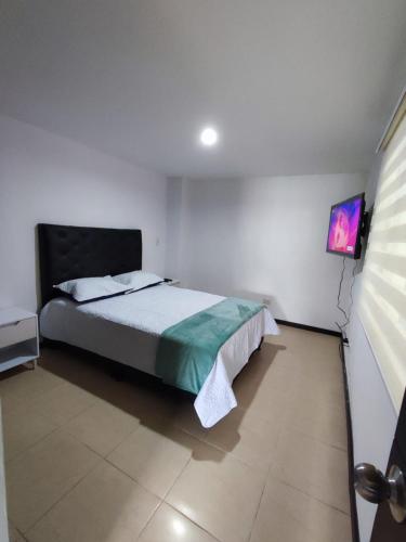 a bedroom with a bed and a flat screen tv at Buena Vista Suites in Armenia