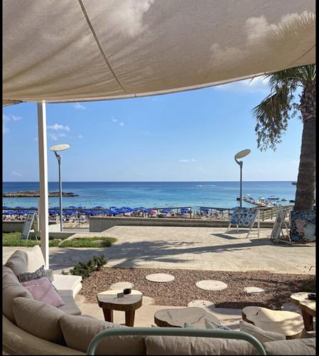 a patio with a couch and tables and the beach at Blue Peter Apartments in Protaras