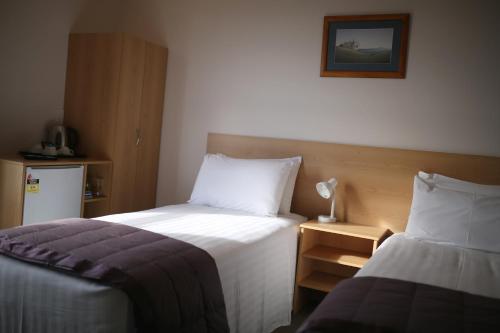 a hotel room with two beds and a lamp at Masonic Hotel in Waitara