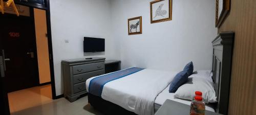 um quarto com uma cama, uma mesa e uma televisão em Smart Tlogomas Syariah em Malang