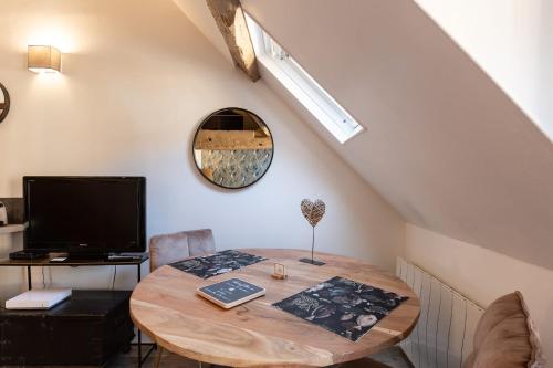 une pièce avec une table en bois avec une télévision et un bureau dans l'établissement La Mezzanine d'Au Sans Pareil- Cosy appartement city center Honfleur, à Honfleur