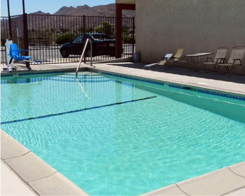 
a swimming pool with a pool table and a chair at High Desert Motel Joshua Tree National Park in Joshua Tree

