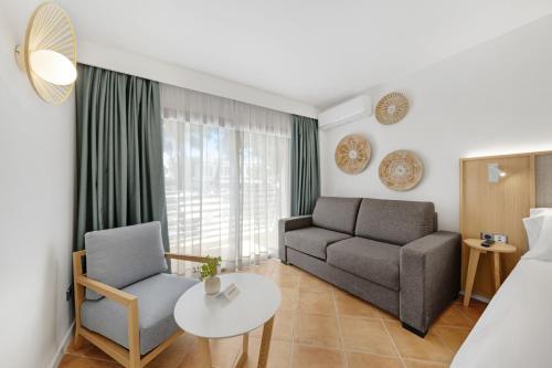 a hotel room with a bed and a couch and a table at Occidental Cala Viñas in Cala Vinyes