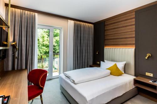um quarto de hotel com uma cama e uma cadeira vermelha em Hotel Am Schloss Aurich - Schlossresidenz em Aurich