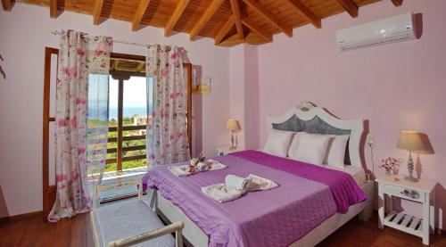 ein Schlafzimmer mit einem Bett mit violetter Bettwäsche und einem Fenster in der Unterkunft ORFEAS HOUSE 2 in Patitiri