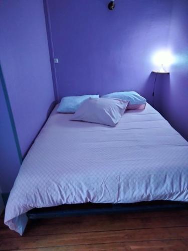 um quarto com uma cama grande com lençóis brancos e almofadas em Le gibergeon em Signy-lʼAbbaye