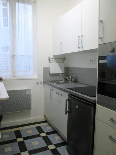 une cuisine avec des armoires blanches, un évier et une fenêtre dans l'établissement LES PAILLETTES, à Le Touquet-Paris-Plage