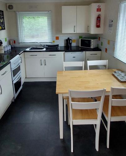 a kitchen with a wooden table and white cabinets at 89 Lower Lakeside - Glan Gwna Holiday Park in Caernarfon