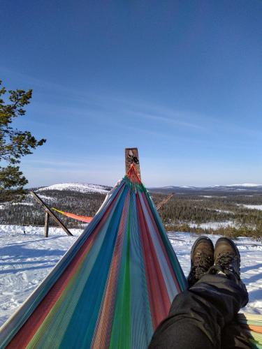 a person laying on a hammock in the snow at Isokelo Log Apartments in Salla