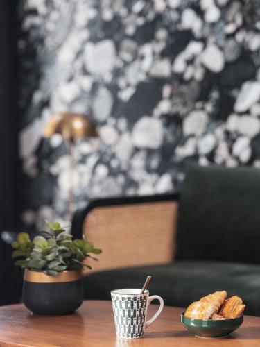 a table with a cup of coffee and a plate of bread at Maisons du Monde Hotel & Suites - Nantes in Nantes