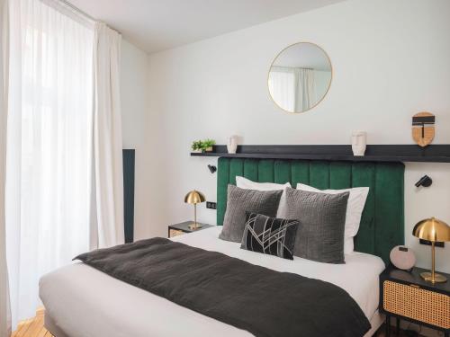 a bedroom with a large bed with a green headboard at Maisons du Monde Hotel & Suites - Nantes in Nantes