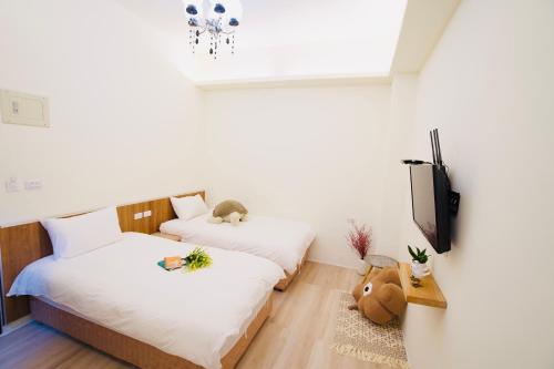 two beds in a room with white walls and a tv at It's Mine Hostel in Taitung City