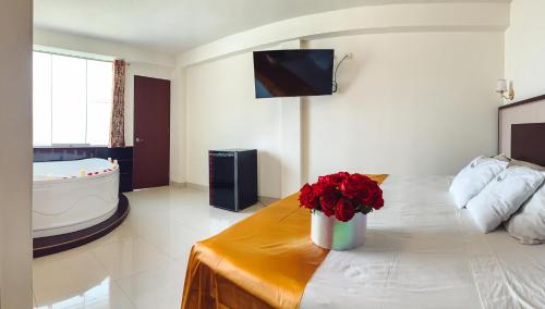 a living room with a bed and a vase of flowers at Hotel La Mansion in Tacna