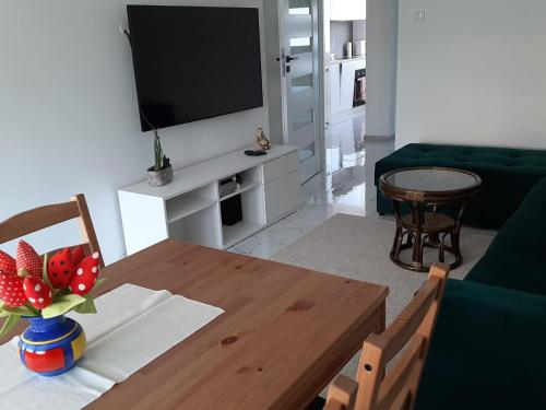 ein Wohnzimmer mit einem Tisch und einem TV in der Unterkunft Apartament na 9. piętrze in Oświęcim