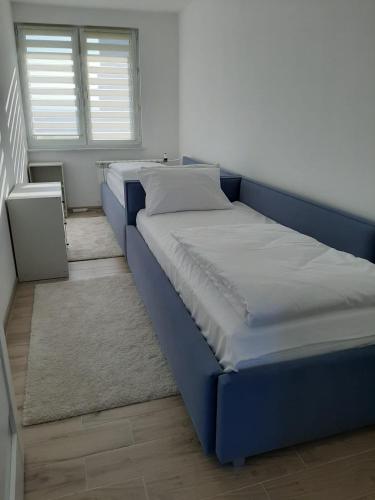 ein blaues Bett in einem Zimmer mit Fenster in der Unterkunft Apartament na 9. piętrze in Oświęcim
