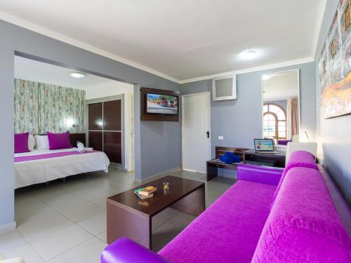 a living room with a purple couch and a bed at eó Suite Hotel Jardin Dorado in Maspalomas