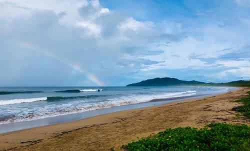a beach with a rainbow in the sky and the ocean at Hotel El Manglar in Playa Grande