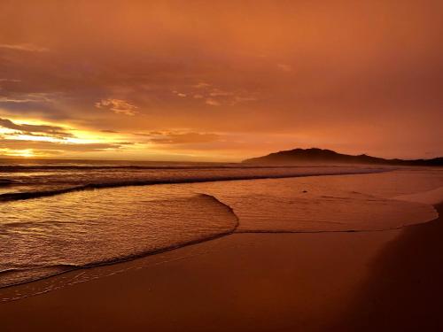 a sunset on the beach with the tide coming in at Hotel El Manglar in Playa Grande