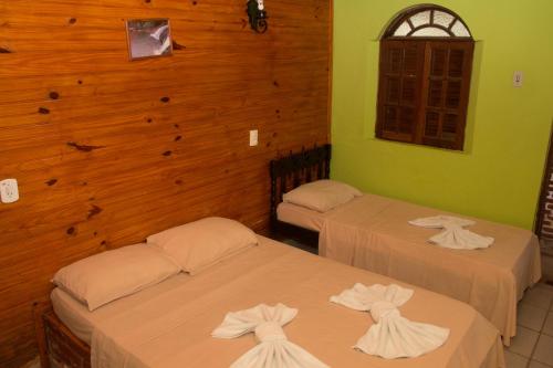 two beds in a room with wooden walls at Pousada do Bezerra in Alto Caparao