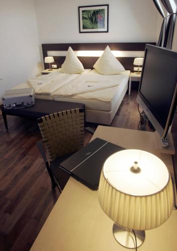 a room with a bed and a table with a tv at Hotel im Kornspeicher in Marburg an der Lahn