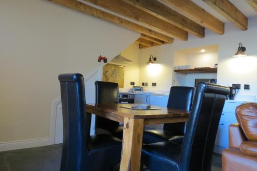 a kitchen with a wooden table and black chairs at Farthing Cottage in Bishop Auckland