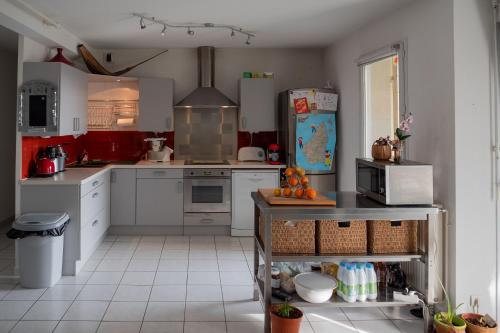 een keuken met witte kasten en een koelkast bij Chambre d'hôte Sainte Émilie in Annonay