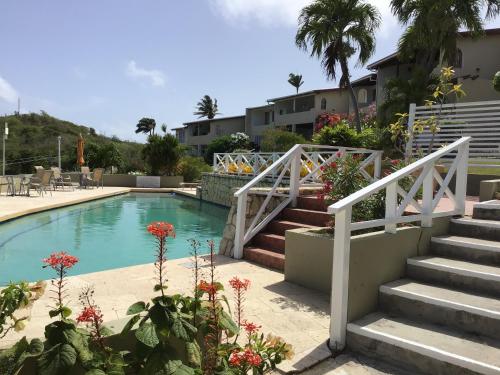 a swimming pool with stairs and flowers in a yard at Swimming Pool- Balcony Veranda- Sea & Sunset Views in Dickenson Bay