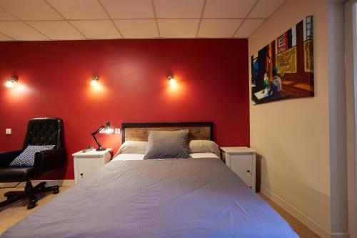 a bedroom with a bed and a red wall at hotel de la paix in Pamiers