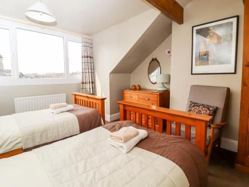 a bedroom with two beds and a chair and a window at Craven House in Skipton