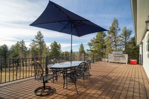 a table and chairs with an umbrella on a deck at 24 Quiver Circle Spectacular Mountain View 5 Acres PIKES PEAK in Florissant