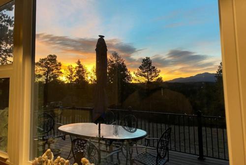 a table and chairs on a balcony with a sunset at 24 Quiver Circle Spectacular Mountain View 5 Acres PIKES PEAK in Florissant