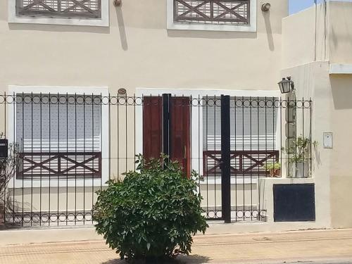 a black gate with a bush in front of a building at Departamento Arana in Tandil