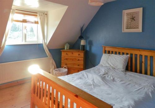 a bedroom with a wooden bed and a window at Castle Cottage By The Beach in Greencastle