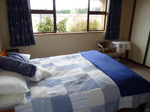 Schlafzimmer mit einem blauen und weißen Bett und einem Fenster in der Unterkunft Lesley's Bed and Breakfast in Cromwell