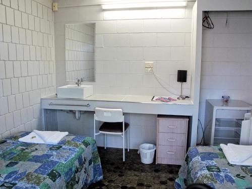a bathroom with a sink and a desk with two beds at CStay in Picnic Bay