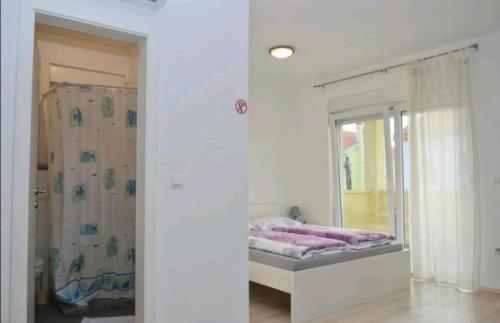 ein weißes Zimmer mit einem Bett und einem Spiegel in der Unterkunft Urnebes in Zadar
